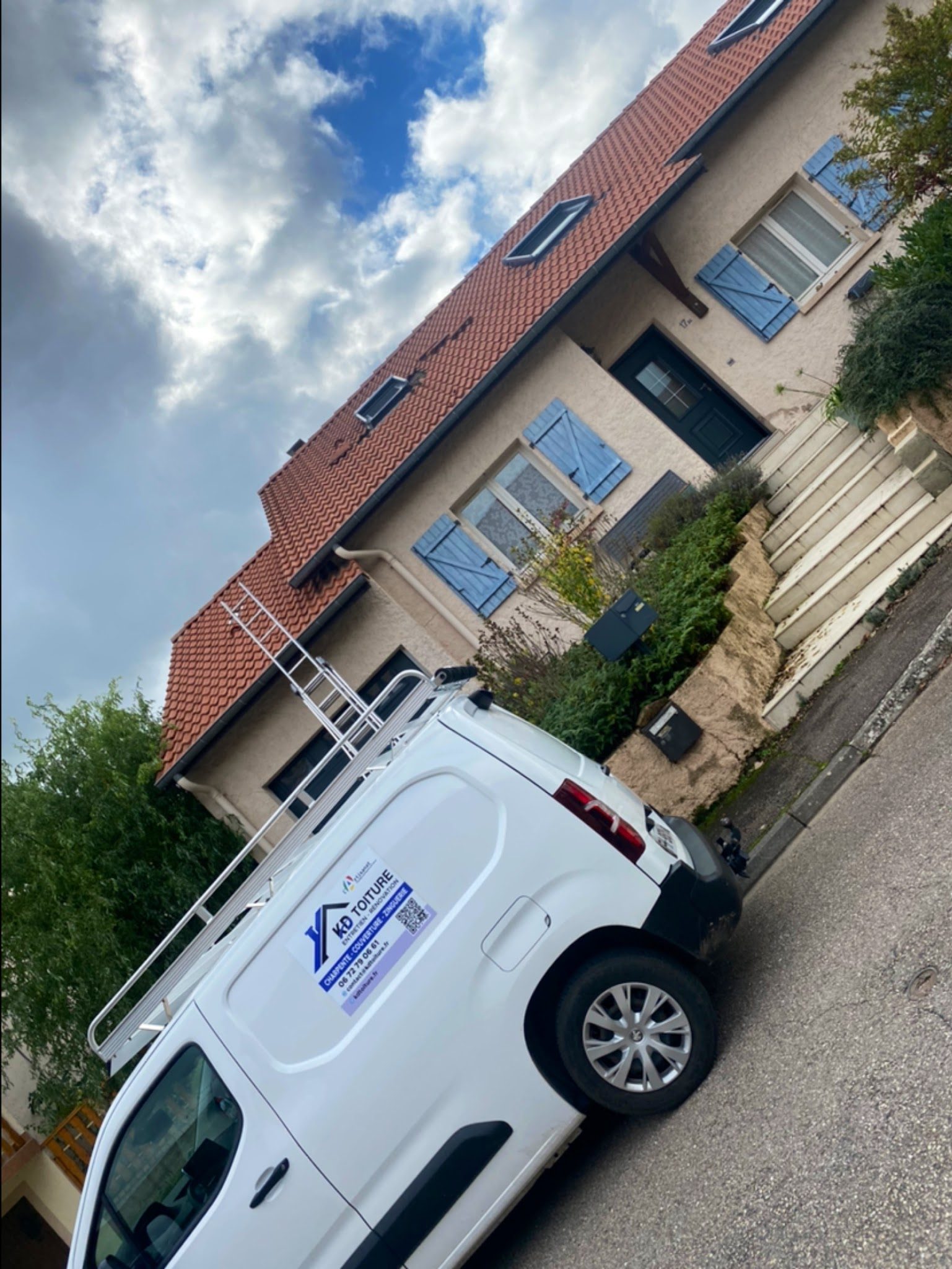 La camionnette KD Toiture devant une maison aux tuiles rouges et aux volets bleus